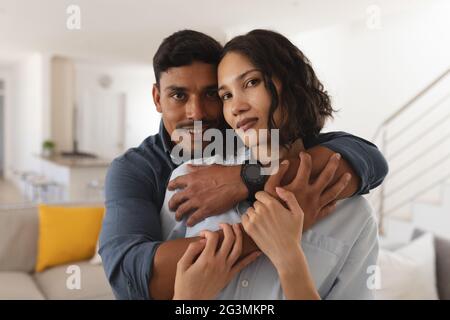 Portrait of happy hispanic couple embracing in living room, looking to camera Stock Photo