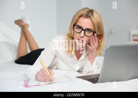Businesswoman working laptop in bed Stock Photo