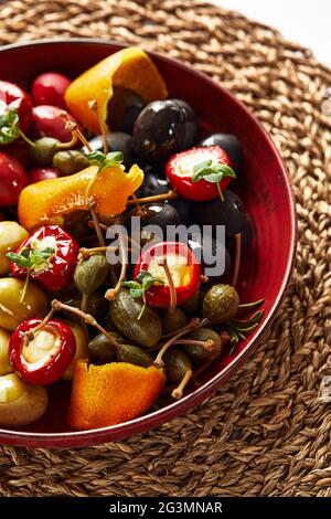 Pickled vegetables in a plate, olives, black olives, stuffed peppers, radishes. Assorted vegetables, vegetables with spices in oil close-up. Stock Photo
