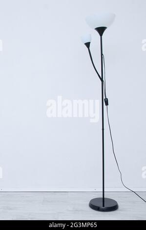 Floor electric black lamp with white shades in the interior of the room. Stock Photo