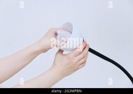 Caucasian girl twists an energy-saving lamp into a white electric lamp. Stock Photo