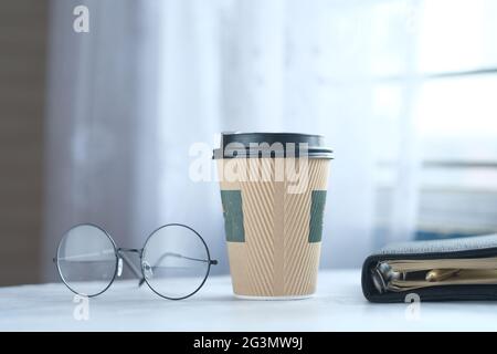 take away paper , eyeglass and notepad on table  Stock Photo