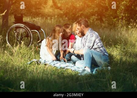 Happy family taking selfie on the picnic in park. Paraplegic Stock Photo