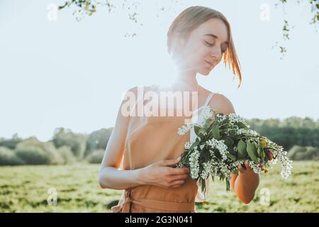 Young girl florist in apron is creating a floral bouquet as a gift from blooming wildflowers. Florist at work. Female is holding flower bouquet Stock Photo