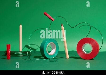 Creative art set pencils, red and green tape, pins, green wire on green back Stock Photo