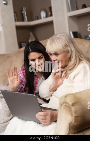 Smiling daughter teaches her senior mother how to use laptop Stock Photo