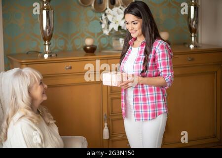 Smiling daughter is giving to her mother a lovely present Stock Photo