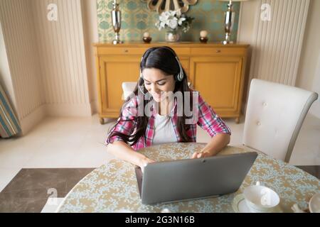 Beautiful woman works at her laptop wearing headsets Stock Photo