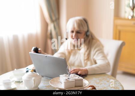 Senior woman plays video games with joystick on a laptop Stock Photo