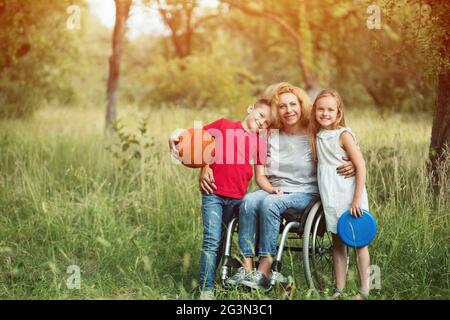 Family portrait. Woman in a wheelchair with her family outdoors. Stock Photo