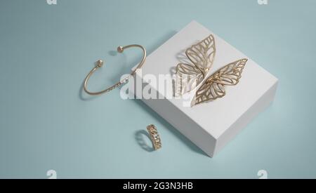 Butterfly shape golden earrings and bracelet on white box with chain shape ring Stock Photo