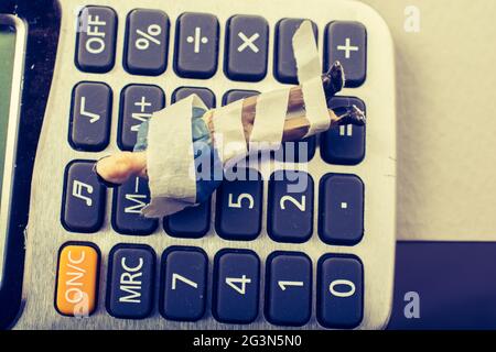 Tiny figurine of man model  wrapped in bandages on calculator Stock Photo