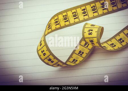 Yellow measuring tape on lined paper Stock Photo