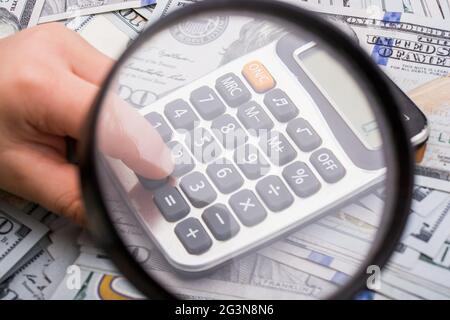 Magnifying glass  and calculator over the US dollar banknotes Stock Photo