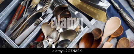 Vintage forks, spoons and knives in a dark old wooden box on a gray concrete or stone background. Selective focus.Top view. Copy space. Stock Photo