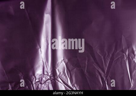 A gray-pink crumpled glossy surface. Shot Of colored Packing Texture. Uneven Abstract Background with Copy Space. Stock Photo
