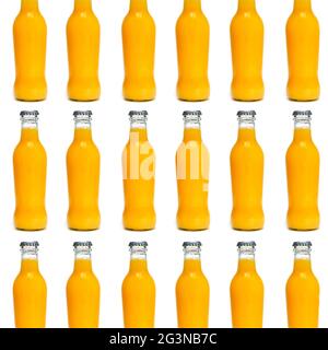 some glass bottles filled with an orange-colored fruit and vegetable beverage arranged in lines forming a mosaic on a white background Stock Photo