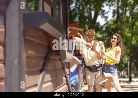 Happy attractive young couple romantically eating a fresh pizza outdoors. Stock Photo