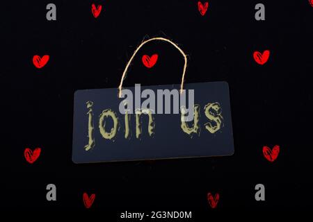 Join us label on a black notice board  and red hearts Stock Photo