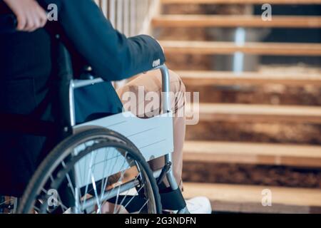 Man in wheelchair stopped near stairs Stock Photo