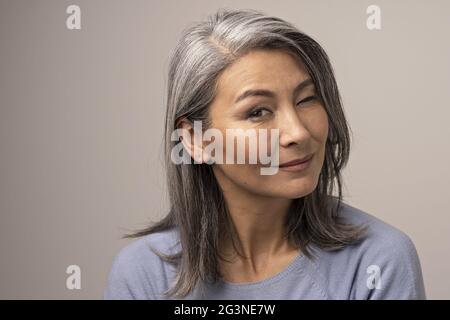 Charming Asian mature woman smiles at camera Stock Photo