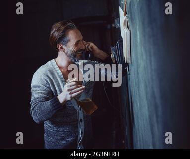 Happy drunk man talks on a vintage rotary telephone Stock Photo