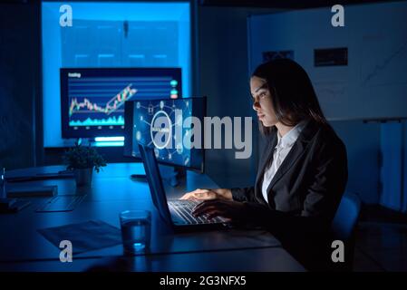 Serious employee typing on laptop while analyzing data in office Stock Photo