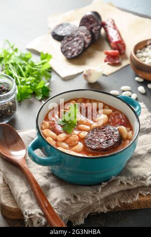 Asturiana traditional fabada with haricot, blood sausage on brown background. Vertical orientation. Tasty traditional spanish warming dinner. Stock Photo
