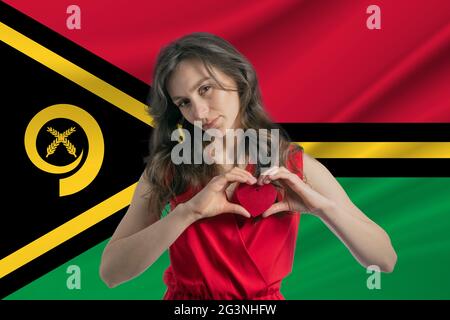 Love Vanuatu. A girl holds a heart on her chest in her hands against the background of the flag of Vanuatu. The concept of patriotism Stock Photo