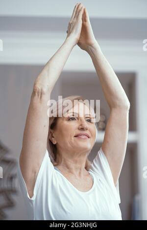 Beautiful woman holds hands pressed together above head Stock Photo
