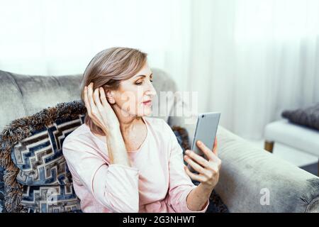 Beautiful mature woman takes selfie at home Stock Photo