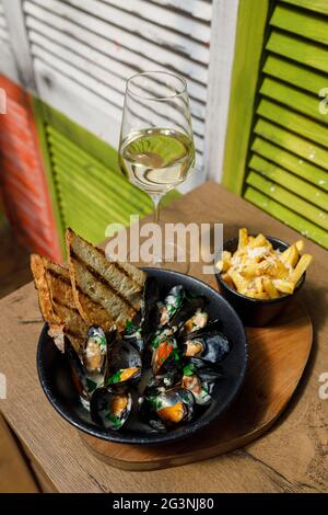 Boiled mussels in copper cooking dish on dark wooden background close up