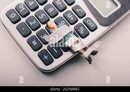 Tiny figurine of man model  wrapped in bandages on calculator Stock Photo