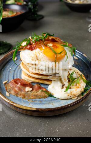 Pancakes with bacon, fried eggs and melted cheese Stock Photo