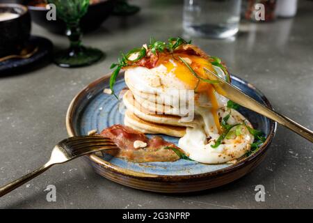Pancakes with bacon, fried eggs and melted cheese Stock Photo