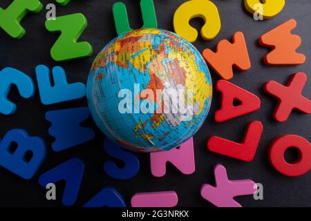 Globe model on colorful letters on a black background Stock Photo