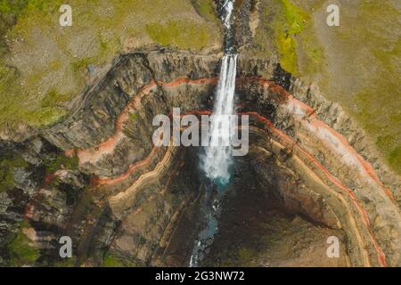 Aerial top down view of Hengifoss waterfall in East Iceland. The third highest waterfall in Iceland and is surrounded by basaltic strata with red
