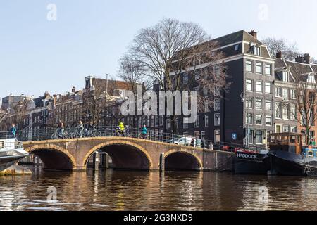 Amsterdam, Netherlands -12 March 2016: Bridge pedestrians and cyclists over the Amstel canal. Typical dutch houses. Stock Photo