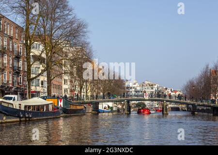 Amsterdam, Netherlands -12 March 2016: Bridge pedestrians and cyclists over the Amstel canal. Typical dutch houses. Stock Photo