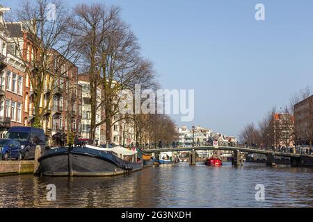 Amsterdam, Netherlands -12 March 2016: Bridge pedestrians and cyclists over the Amstel canal. Typical dutch houses. Stock Photo