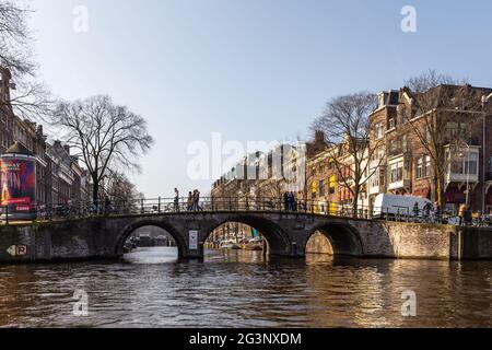 Amsterdam, Netherlands -12 March 2016: Bridge pedestrians and cyclists over the Amstel canal. Typical dutch houses. Stock Photo