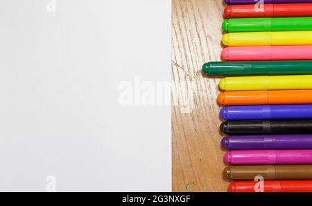 A set of colored markers and a sheet of white paper on the table. Stock Photo