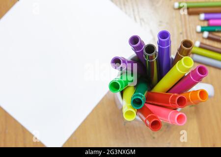A set of colored markers and a sheet of white paper on the table. Stock Photo