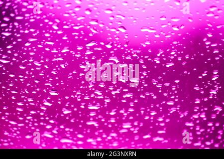 Droplet-filled window glass with a deep purple color throughout the image Stock Photo