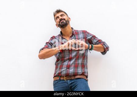 Portrait of a man making heart sign on chest isolated on white wall background. Stock Photo