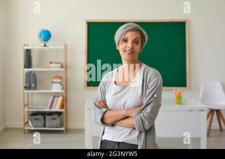 Teacher at college school. Senier teacher woman looking at the camera while standing in class. Stock Photo