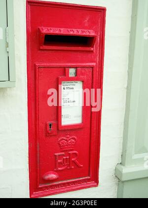a traditional red Royal Mail postbox set into the wall of the Post Office at Napton Stock Photo