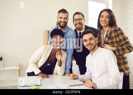 Happy diverse business team looking at camera and smiling after work meeting in office Stock Photo