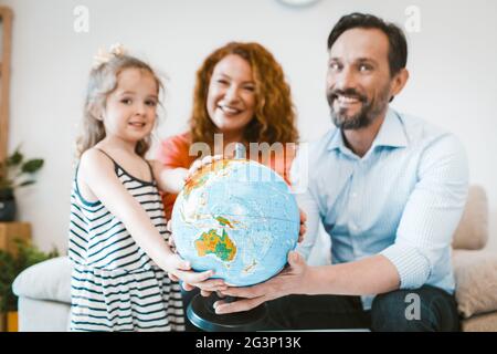 Mom, dad and little girl planning vacation, holding globe. Stock Photo