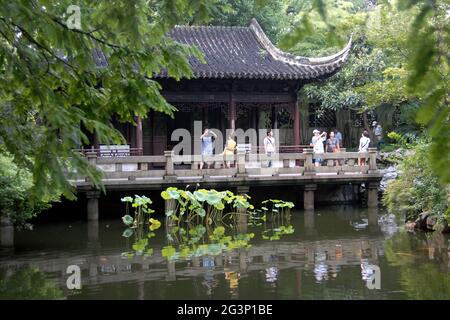 Yu Yuan Garden in the Old Town of Shanghai, China. A traditional Chinese garden with trees, rocks and water. People take photos near a pavilion. Stock Photo